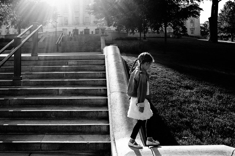 Girl balances on Capitol steps in morning sunlight 