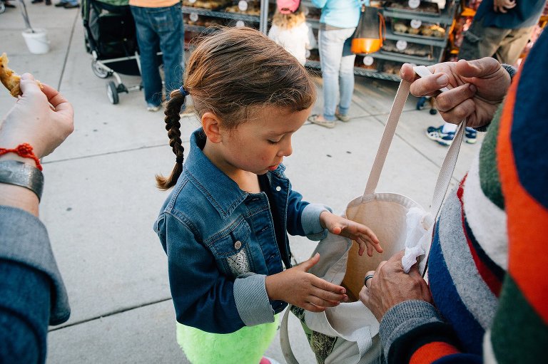 Girl looks through canvas produce bag at farmer's market