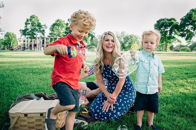 Mom and two boys blow bubbles at park 