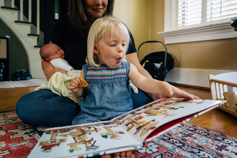 Daughter reads book with surprise expression. 