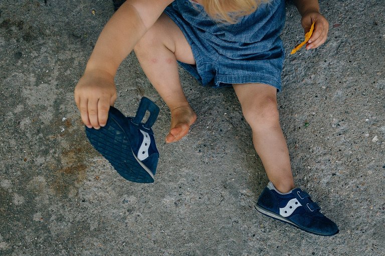Toddler daughter puts on own shoes. 