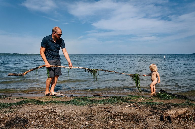 Dad and daughter find stick with seaweed attached. 