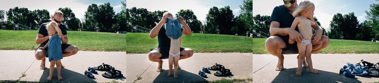 Dad helps daughter change out of clothes to swim in lake. 
