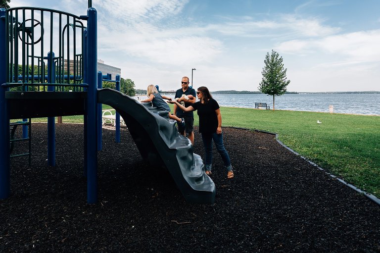 Family play with toddler girl on summer day near a lake. 