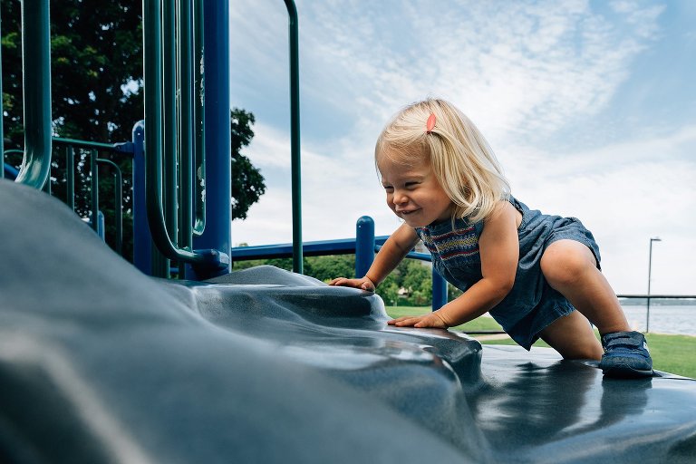 Girl climbs play structure on summer day. 