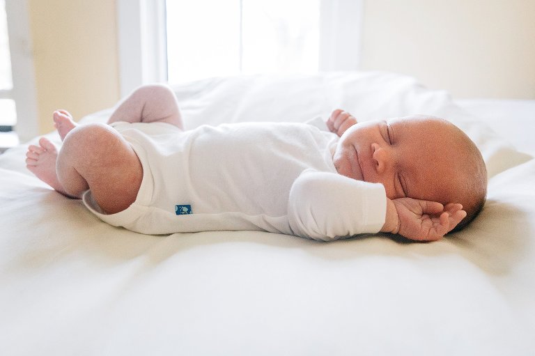 Newborn baby sleeps on white bed. 