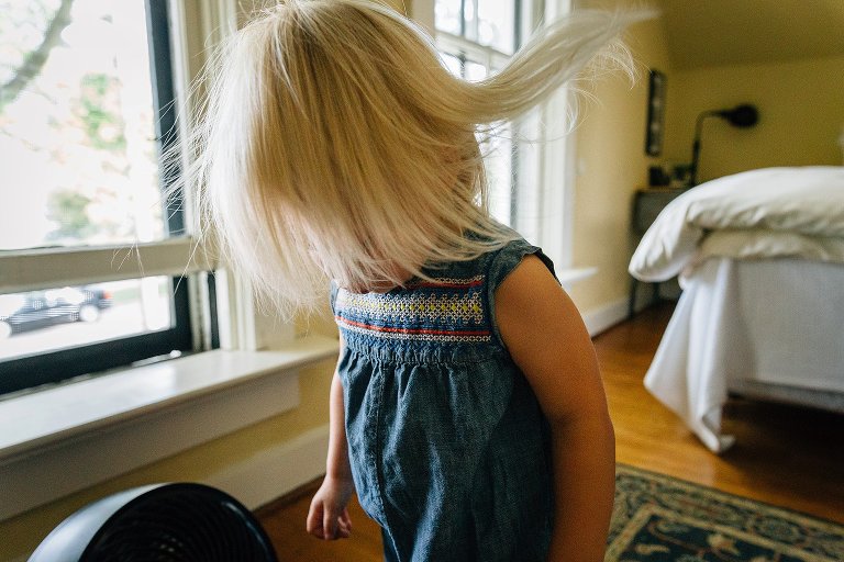 Fan blows toddler's hair--color. 