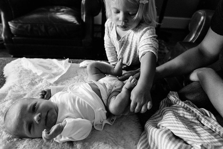 Toddler girl helps change sister's diaper. 
