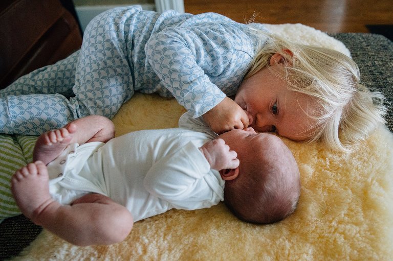 Girl inspects newborn sister's nose. 