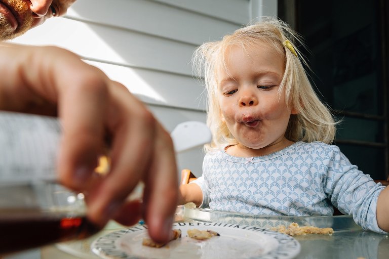 Daughter puckers mouth as dad pours more syrup on her plate 