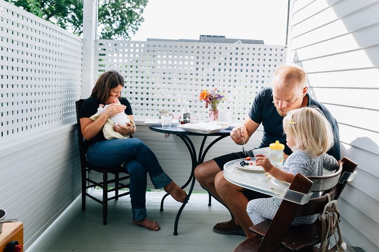 Family eats breakfast together on back porch on summer morning.