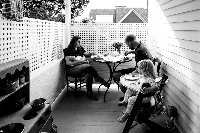 Family eats breakfast together on back porch on summer morning. 