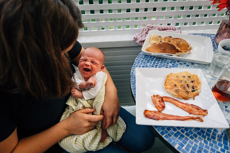 Newborn cries while Mom has full breakfast in front of her, untouched. 