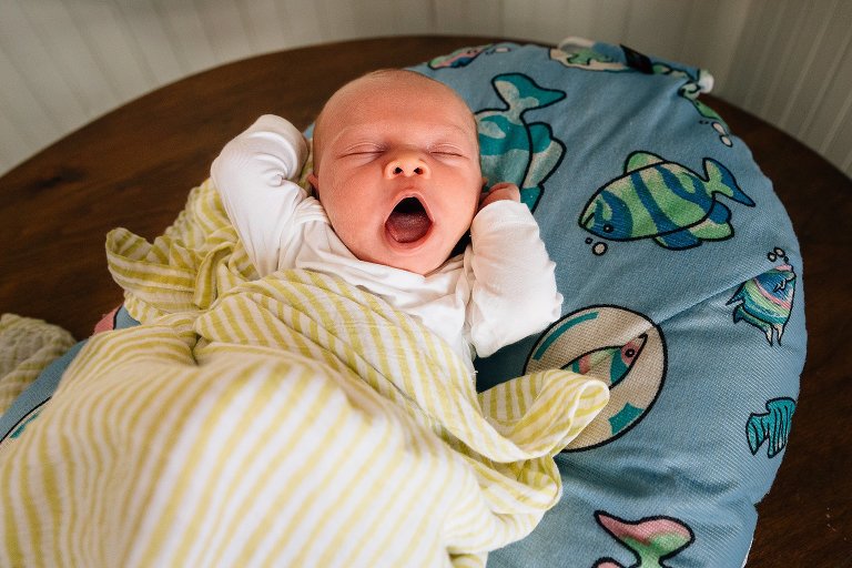 Sleeping newborn stretches and yawns.