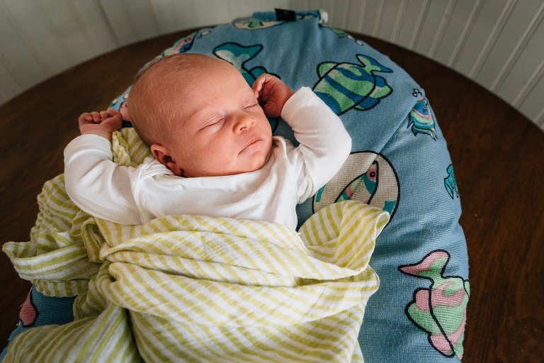 Newborn daughter sleeps with arms above head. 