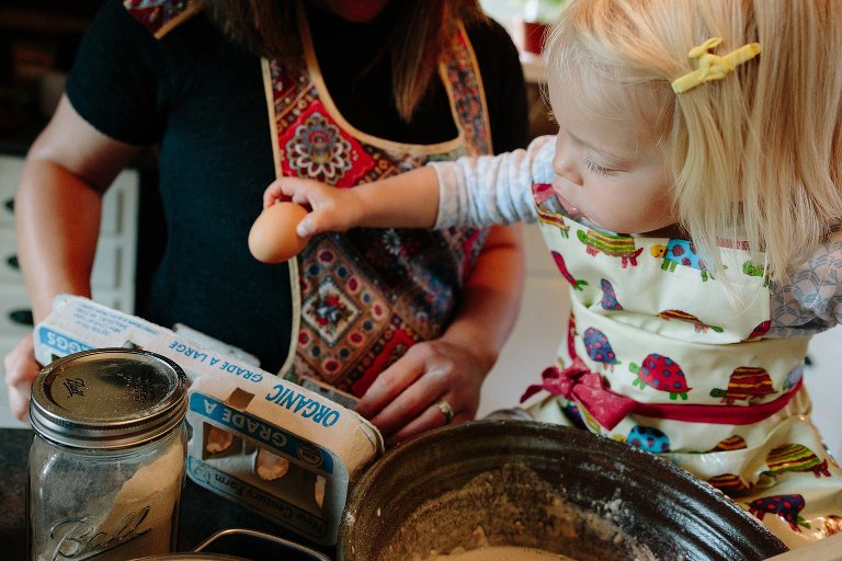 Daughter grabs egg from egg. carton for pancakes. 