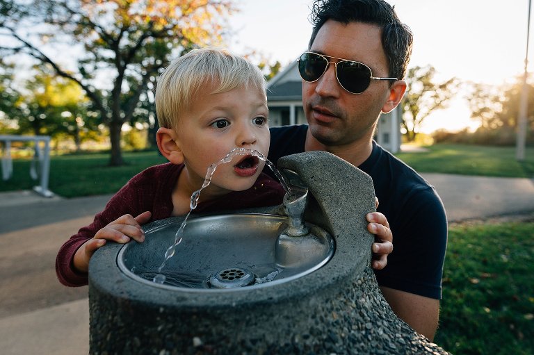preschool boy gets a drink of water from fountain, Dad supports. 