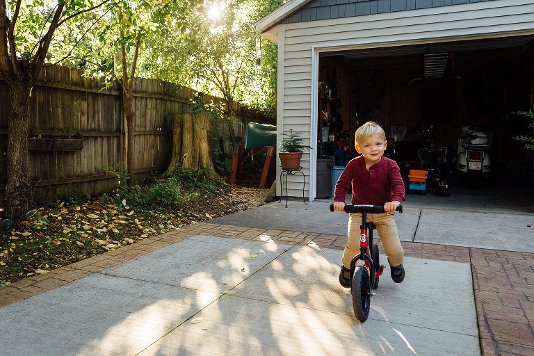 Preschool boy rides a balance bike in his driveway 