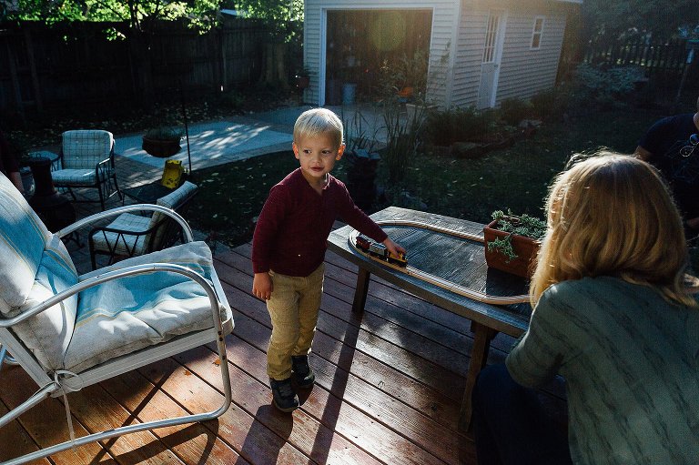 preschool boy plays with toy train in his backyard