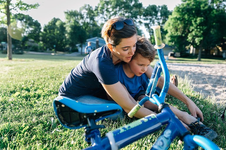 Mom helps boy with his shoes at the park. 