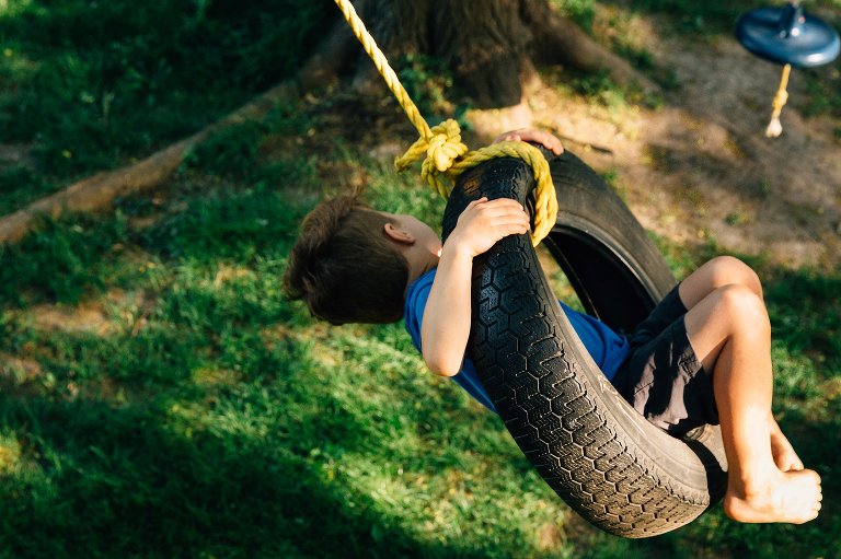 top down view of young boy on a tire swing in backyard