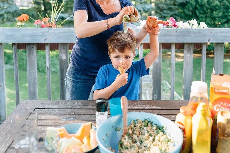 Mother takes one of her son's hands and washes with a washcloth while he eats ice cream with the other hand