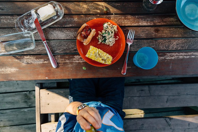 Top down view of colorful plates and bowls filled with family dinner foods.
