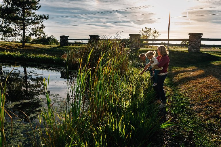 Dad, Mom, and young girl exploring the cattails and pond life on their property. 