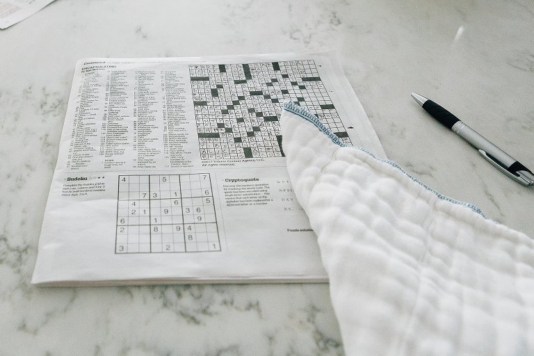 NYT crossword puzzle, more than 3/4th complete. Baby burp cloth tossed over it. 