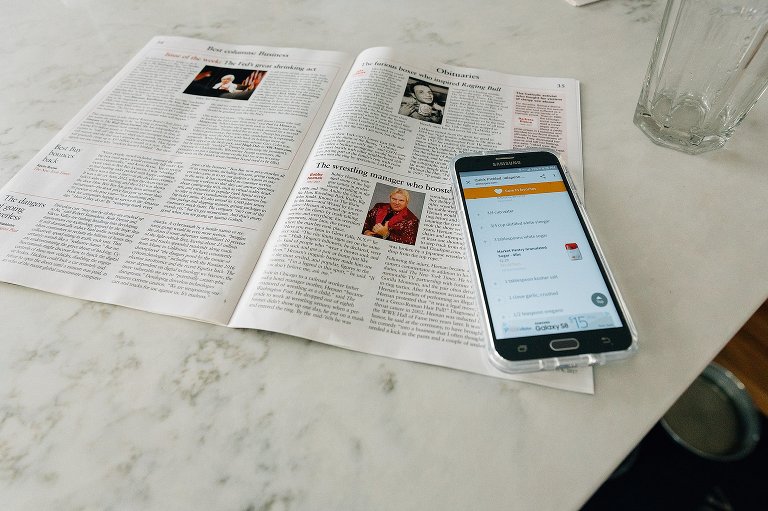 Recipe shows "Quick Pickled Jalapenos" on a phone. Phone sits on top of open, Sunday NYT. 