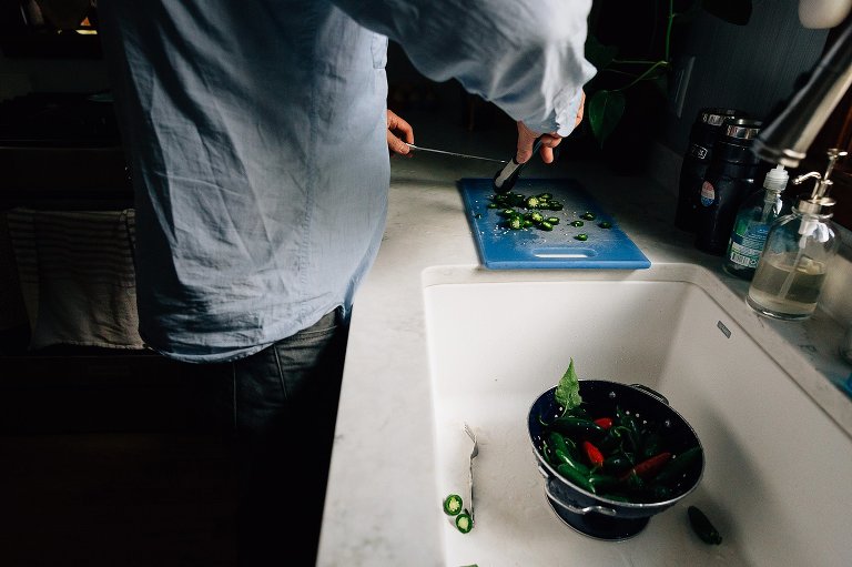 Man slices jalapenos on a blue cutting board. 