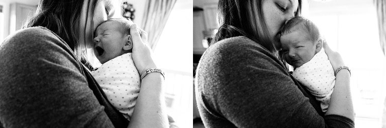 Black and white. Mom consoles crying newborn; newborn baby settles and looks toward camera. 