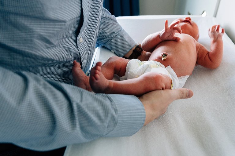 Dad preparing to change newborn diaper. Attached umbilical cord on belly button.