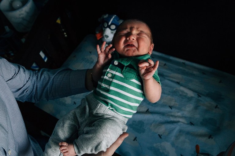 Newborn baby cries being lifted out of crib. 