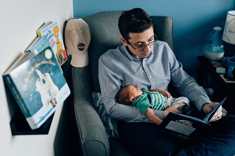 Dad reads a children's board book to sleeping newborn son. 