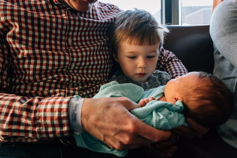 Big brother examines baby sister's hands.