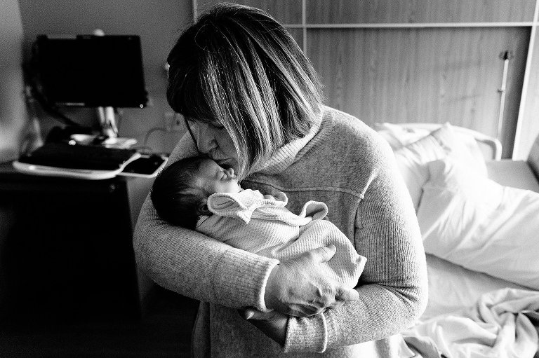 Grandma kisses newborn granddaughter on the forehead. Black and white. 
