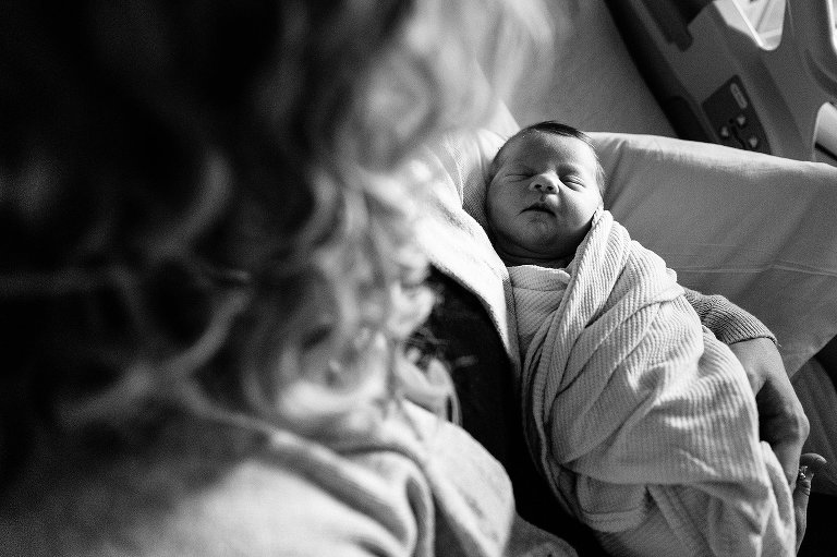 Black and white. Top down view of sleeping newborn in mom's arms. 