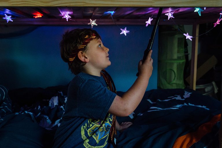 7 year old smiles under his bunk bed. 