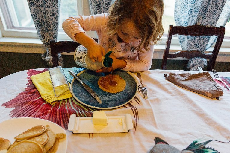 Girl pours syrup on her pancake. 