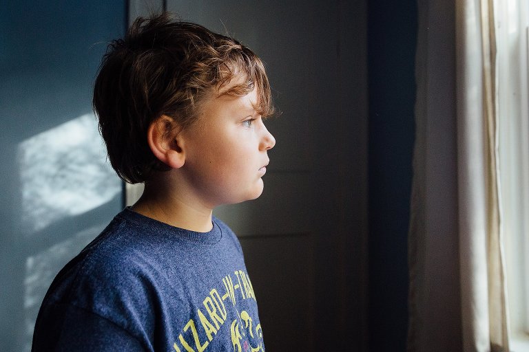7 year old boy looks out a window.