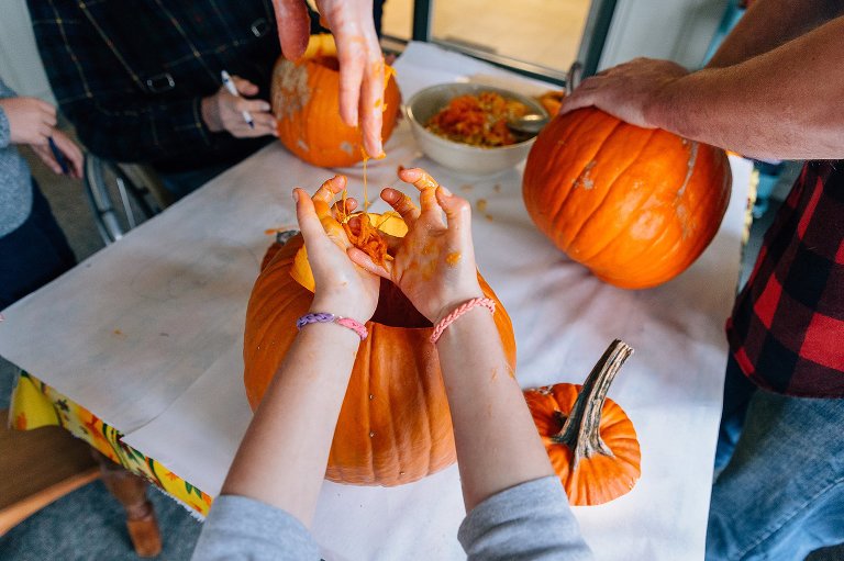 Top down view of girl holding out hands filled with pumpkin guts.