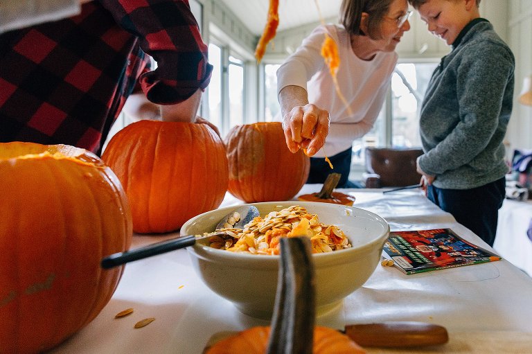 Focus on grandma dropping pumpkin seeds into a bowl while laughing with grandson. 