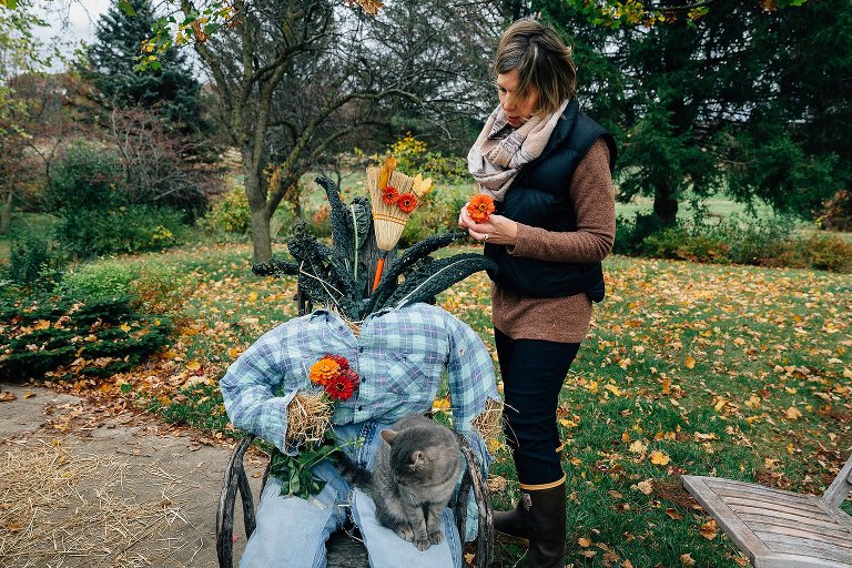 Mom puts flowers for eyes on an elaborate scarecrow. 