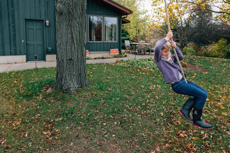 Girl swings on a rope in her backyard during fall. 