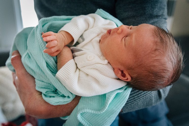 Dad holds sleeping newborn. 