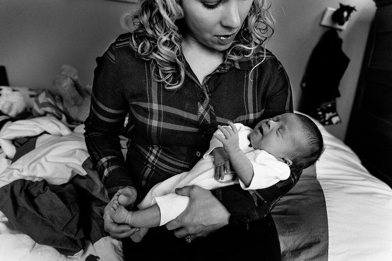 Black and white. Mother holds newborn child and touches her feet. 