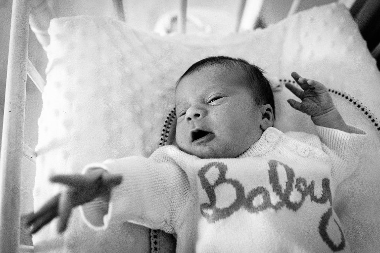 Black and white. Newborn girl stretches arm and fingers 