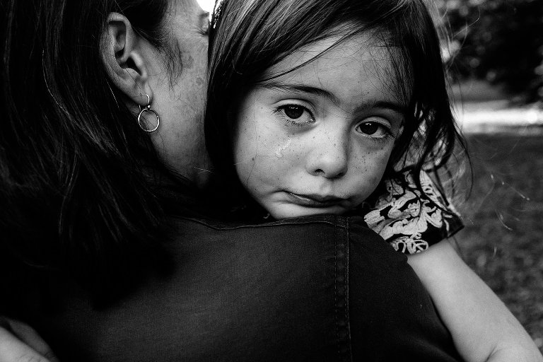 Black and white. Mother holds and comforts teary young daughter.