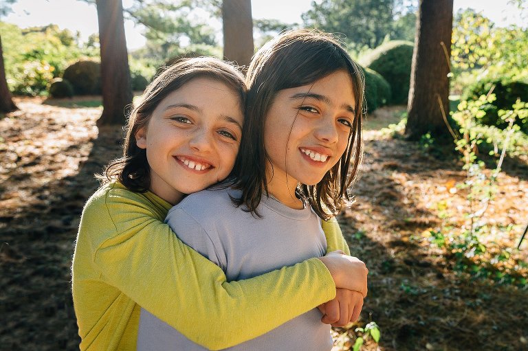 Brothers hug outside, trees in the background.